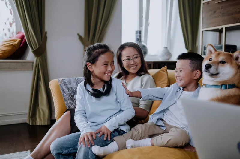 A parent sitting with a child on a couch, reading together quietly.