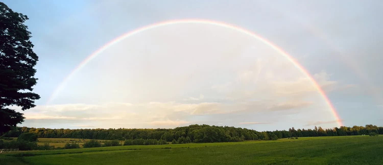 A rainbow over the barn and fields at Farmstead Scattering Garden